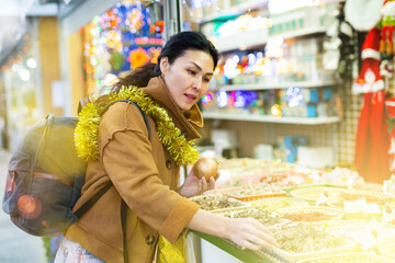 Portrait of smiling happy woman holding christmas ball in her hands on a street market