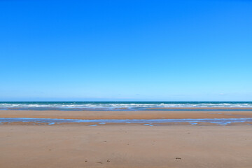 Fototapeta na wymiar The famous fine sandy beach of Omaha beach in Europe, France, Normandy, towards Arromanches, Colleville, in spring, on a sunny day.