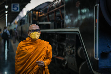 Naklejka na ściany i meble Monk walks into Bangkok Railway Station in Thai call Hua Lamphong with an ancient Pacific type steam locomotives from Japan No.824 in special nostalgic trips.