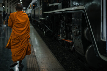 Obraz na płótnie Canvas Monk walks into Bangkok Railway Station in Thai call Hua Lamphong with an ancient Pacific type steam locomotives from Japan No.824 in special nostalgic trips.