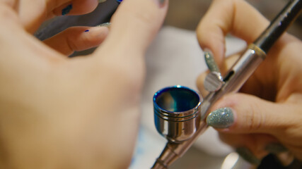 Woman artist learns to paint with airbrush with acrylic dye, paper and easel. Concept modern art, airbrushing, aerography, graffiti, aerosol spray