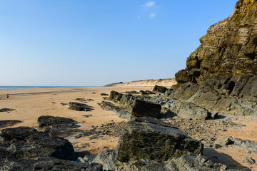 The black rocks of La Vieille Eglise beach in Europe, France, Normandy, Manche, in spring, on a sunny day.