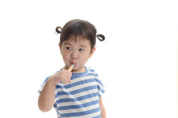 Little asian girl brushing her teeth on white background