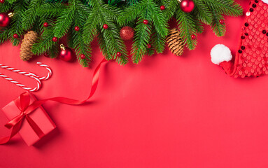 Christmas holiday background with gift box decorations composition, Top view fir green fir tree branches and Xmas ornaments gift box on a red table background, Happy New Year Day concept