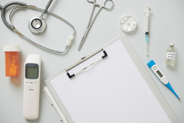 Clipboard with document, stethoscope, non-contact infrared thermometer, tablet and vaccine against coronavirus