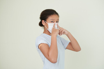 Portrait of serious young teenage girl putting on medical mask and looking at camera