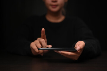 Young woman holding smart phone and touching or pointing to something.