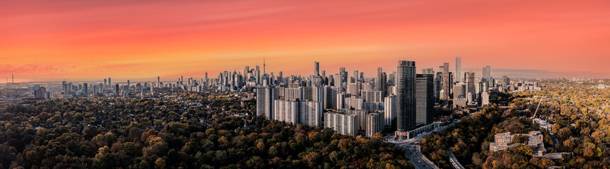 Obraz premium Toronto skyline with city buildings and cntower in view in the fall with yellow trees and red skies 