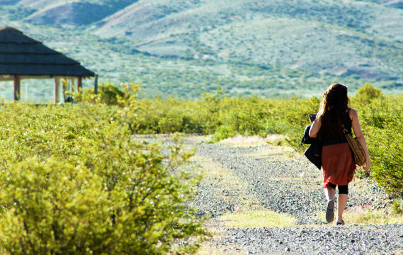 Young woman walks towards the house in the mountains