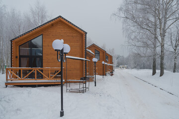 A few tiny houses. Houses stand in a row on a snow-covered street. Winter and frost. Modern architecture.