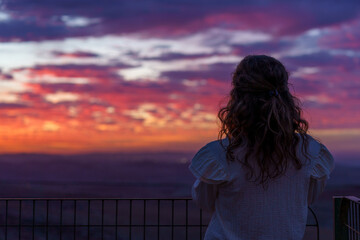 Fototapeta premium Calm young caucasian girl at a beautiful dramatic sunset.
