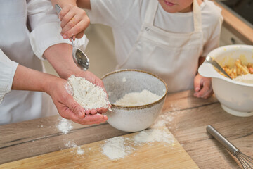 Mother and son cooking apple pie in the home kitchen. A woman and a boy in chef hats and aprons cook with pastries