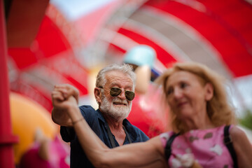 elderly senior couple woman and man having fun and happy together at amusement them park