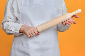 Man chef with dough rolling pin in hand on studio background, copy space