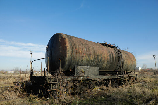 Shallow depth of field (selective focus) image with old and rusty railway oil tanker in the middle of a field on a sunny winter day.