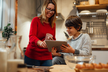 mother and son looking for recipes on digital tablet in kitchen