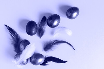 creative Easter composition. purple eggs and feathers on a yellow background. top view. flat lay. Toned trendy color of the year very peri
