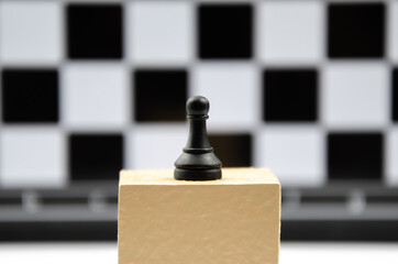 Chess piece - pawn stands on podium against background of chessboard. Goal achievement concept