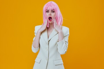 Woman in white suit pink wig posing on yellow background