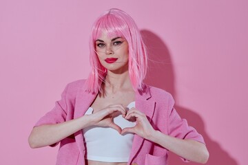 Young positive woman hold hands in the shape of a heart with a pink jacket monochrome shot