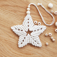 Macrame christmas star in natural color and wooden beards. Cotton rope decor macrame. Woman hobby. Christmas, Winter and New Year concept