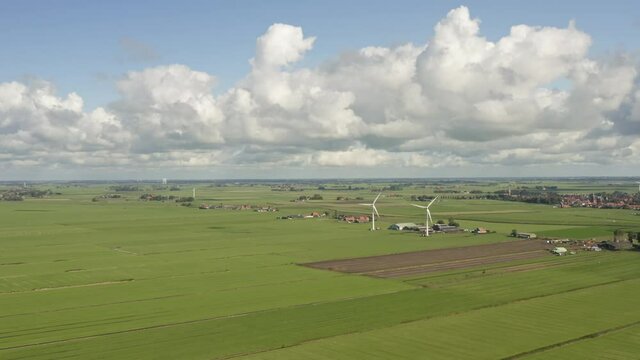 Aerial shot of wind turbines on lush green farmland in Friesland, the Netherlands, on a beautiful sunny summer day
