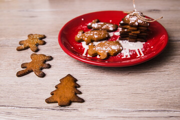 Ginger cookie. Gingerbread. 
Sweets for Santa Claus. Christmas cookies in a red plate and on a wooden table in the shape of a bunny and a Christmas tree. Christmas food mode