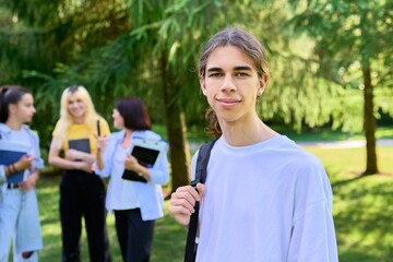 Male student 16, 17 years old with backpack, in school park