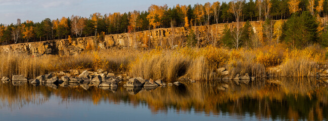 Mixed forest in autumn and stone quarry with granite rocks