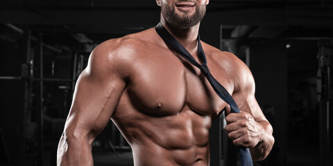 Attractive man with a pumped-up body posing in the gym. Male striptease concept.