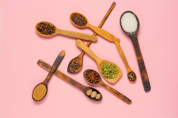 Various herbs and spices in wooden spoons. Flat lay of spices ingredients pepper, salt, cinnamon,star anise, nutmeg, allspice, clove, mustard seeds and cardamom on colorful trendy background. Flat lay