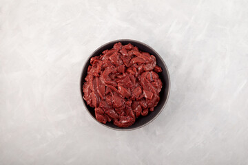 Pieces of raw beef liver in a plate on the table, top view. By-products contain protein, iron and...