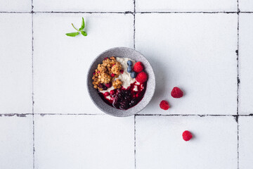 Healthy breakfast cereal porridge with berries and jam in bowl. Closeup view.