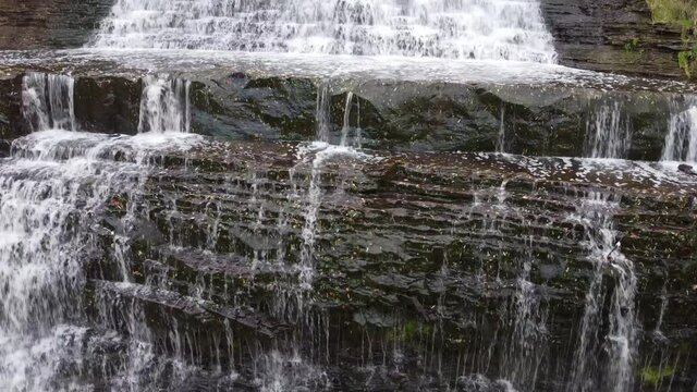 Close up aerial tracking shot capturing the details of rocky steps of cascade spring water flowing downward at Albion Falls, Hamilton, Ontario, Canada.