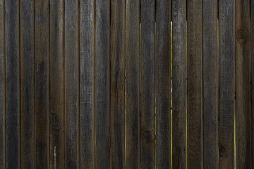 old wooden fence from old boards close-up. in the foreground are large leaves of a beautiful plant. can be used as a photo background. place for text