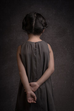 arat portrait of rear view of girl in grey dress and classic braids in hair