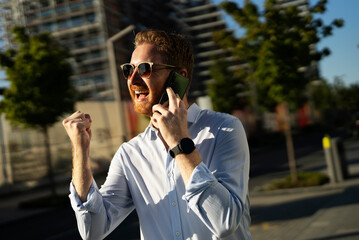 Young happy businessman outdoors. Portrait of handsome man talking to the phone.