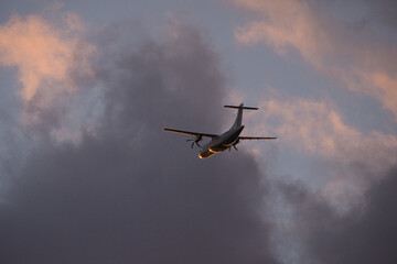 airplane in the evening sky in luminous horizon.
