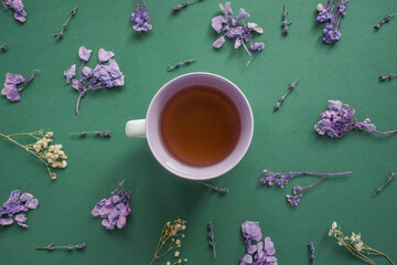 Purple floral pattern around tea cup on green.