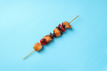 Skewer of tasty chicken shashlik on blue background