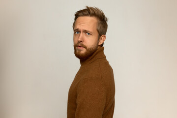 Obraz premium Picture of young brutal manful handsome blond unshaved man turned by his name looking at camera with questioning face expression, frowning with confusion, having stylish haircut and beard