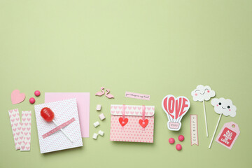 Valentine's Day accessories on green background, top view