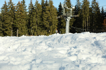 Snow against ski lift and forest, selective focus