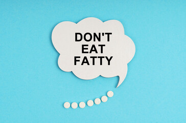 On a blue table are pills and a white plate with the inscription - Don t eat fatty