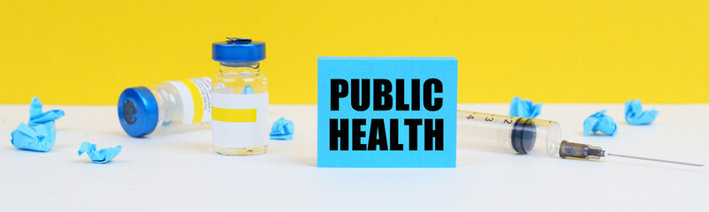 On the table is a syringe, injections and a blue sign with the inscription - PUBLIC HEALTH