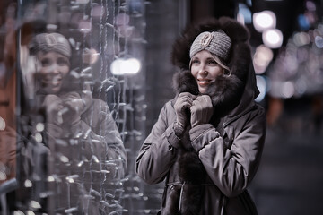 Fototapeta na wymiar happy girl lights evening christmas shopping standing on the street by the shop window