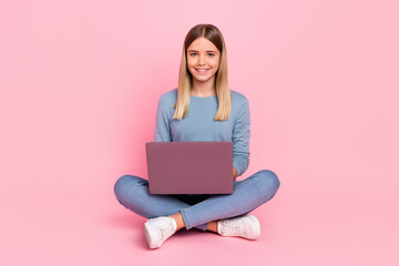 Naklejka premium Full body photo of young girl use laptop sit floor homework courses type isolated over pink color background