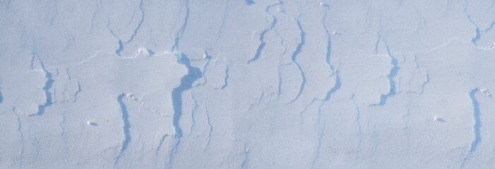 The texture of a cut-off layer of snow with shadows of a panoramic view. Beautiful natural winter background for the holidays New Year, Christmas