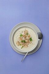 Bowl with mushroom champignon cream soup on violet, purple background. Top view, copy space.