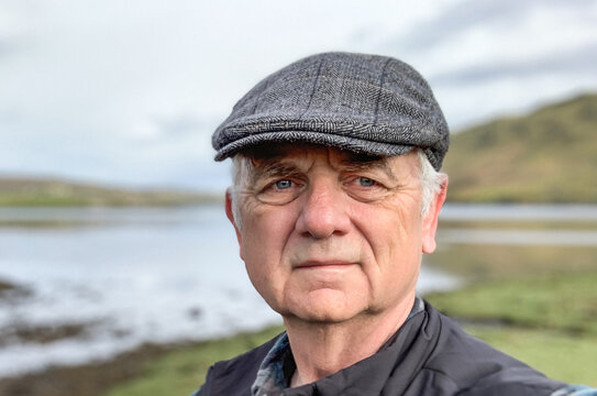 Portrait of a man wearing a flat cap standing in rural landscape, Isle of Skye, Scotland, UK
